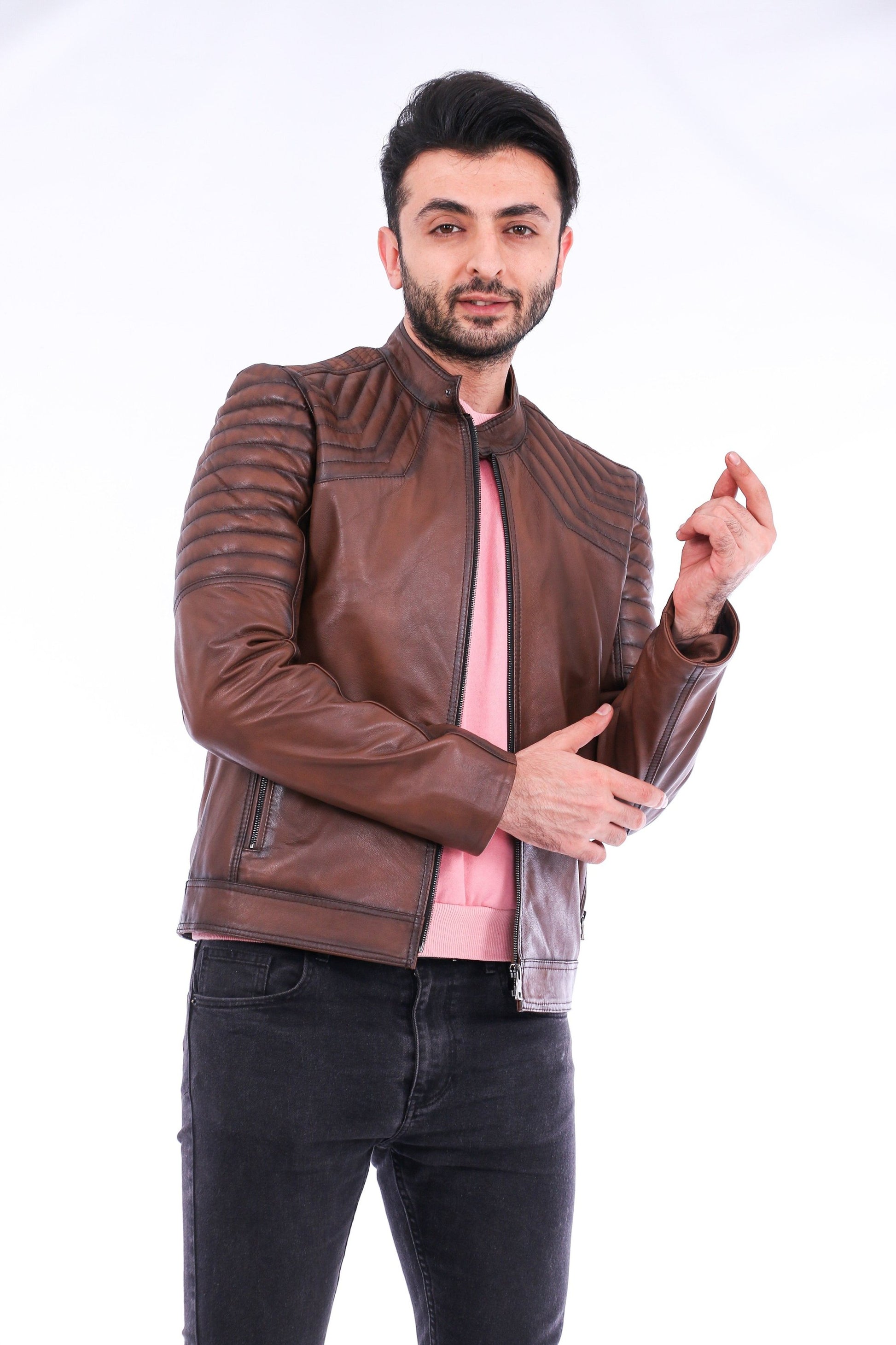 Man wearing a brown leather jacket over a pink shirt on a white background