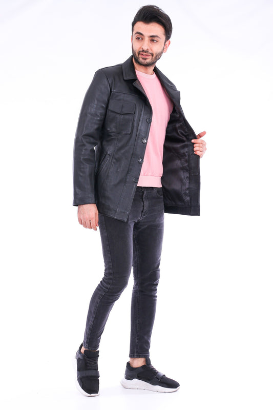 Man wearing a dark jacket over a pink shirt, black jeans, and black shoes on a white background