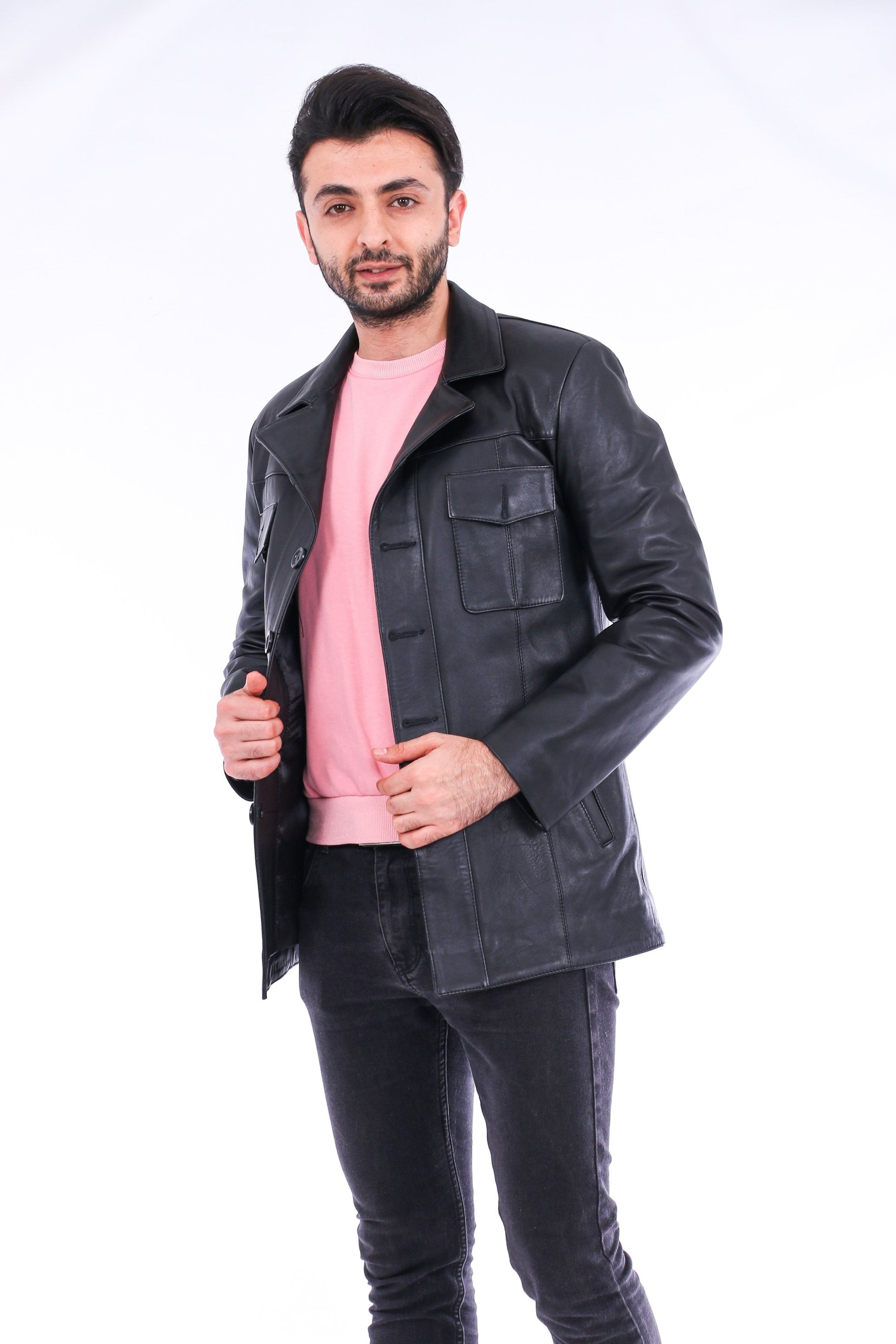 Man wearing a black leather jacket over a pink shirt on a white background