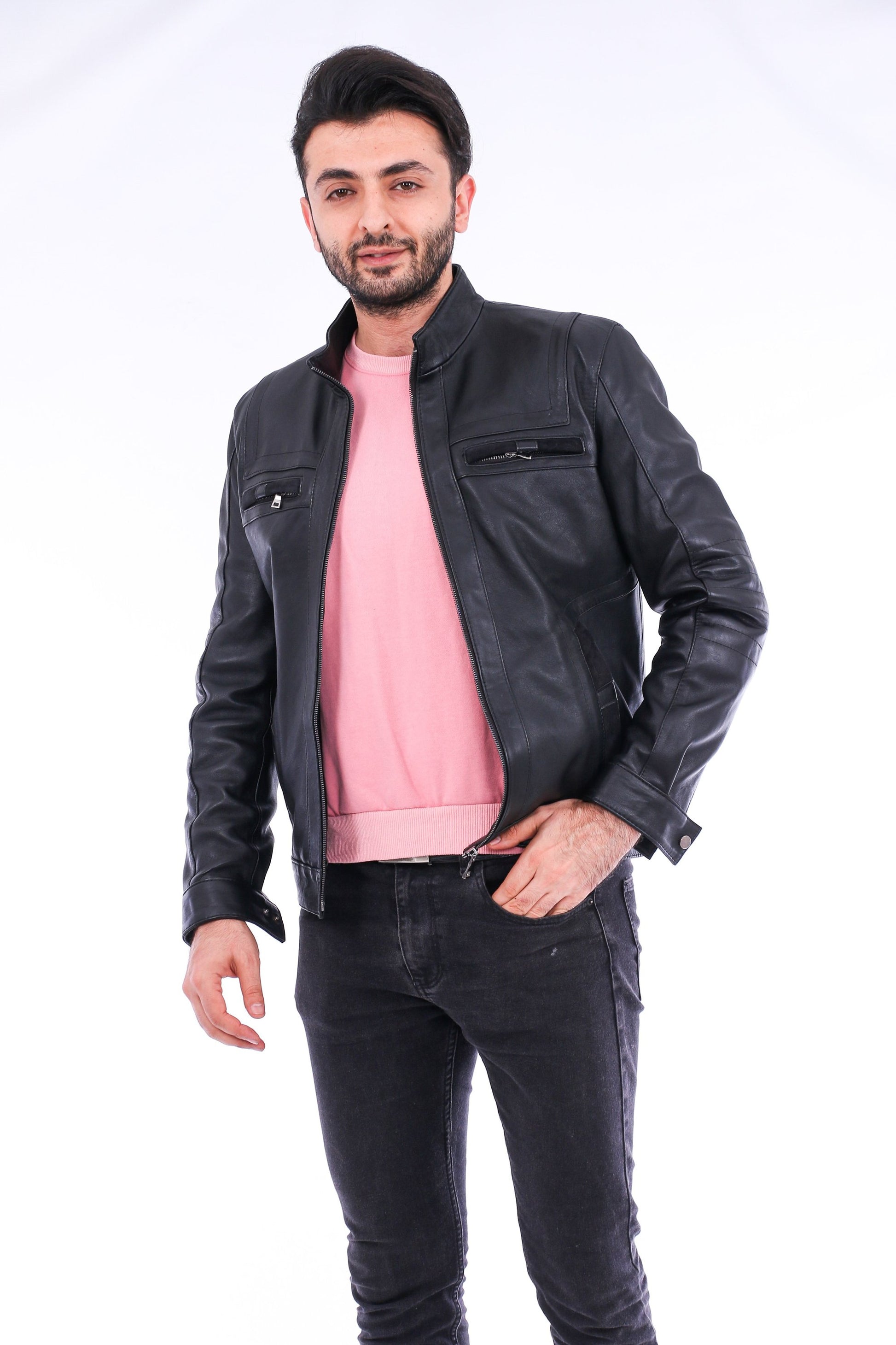 Man wearing a black leather jacket over a pink shirt on a white background