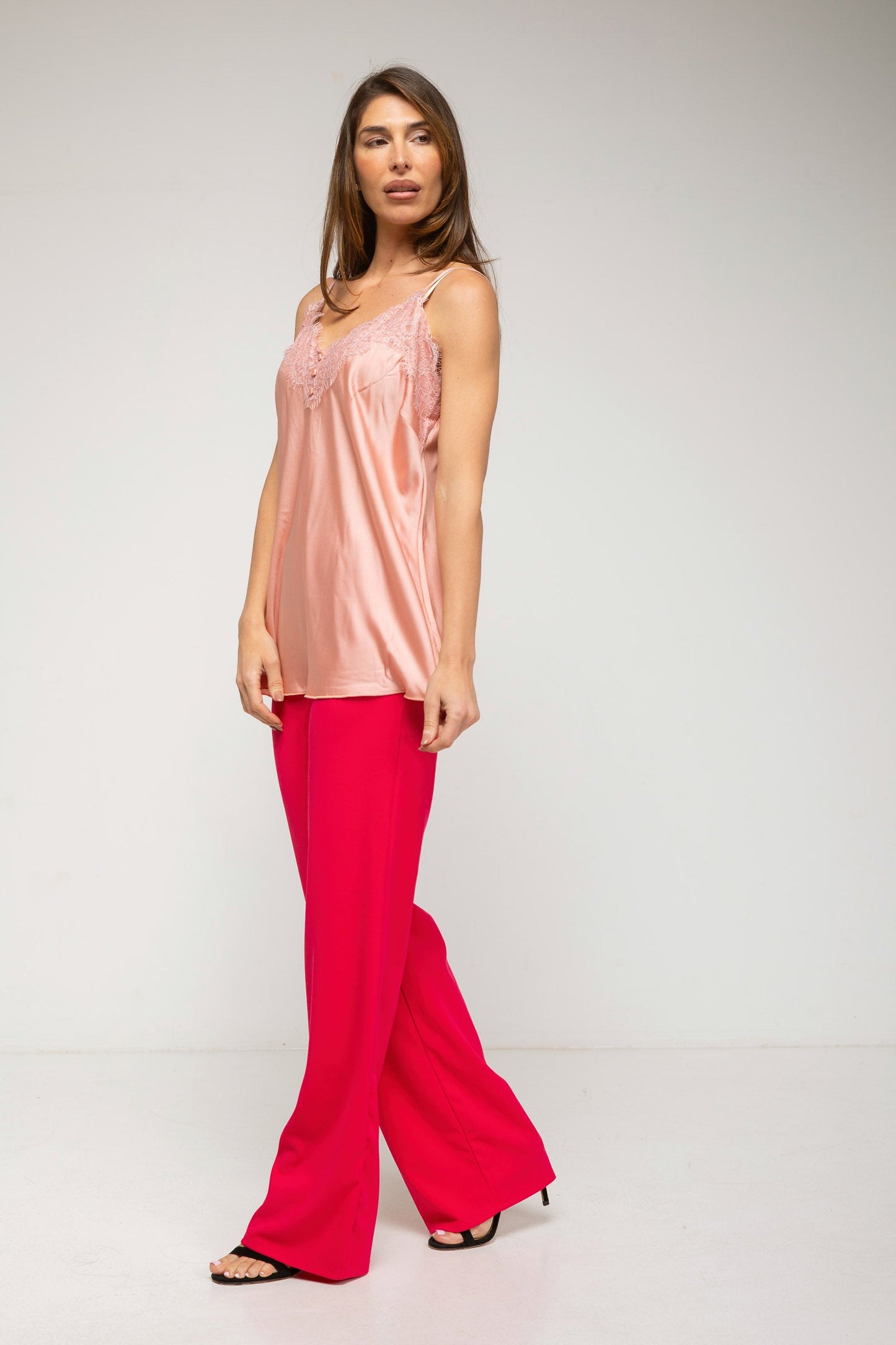 Woman wearing a pink top and red pants on a white background