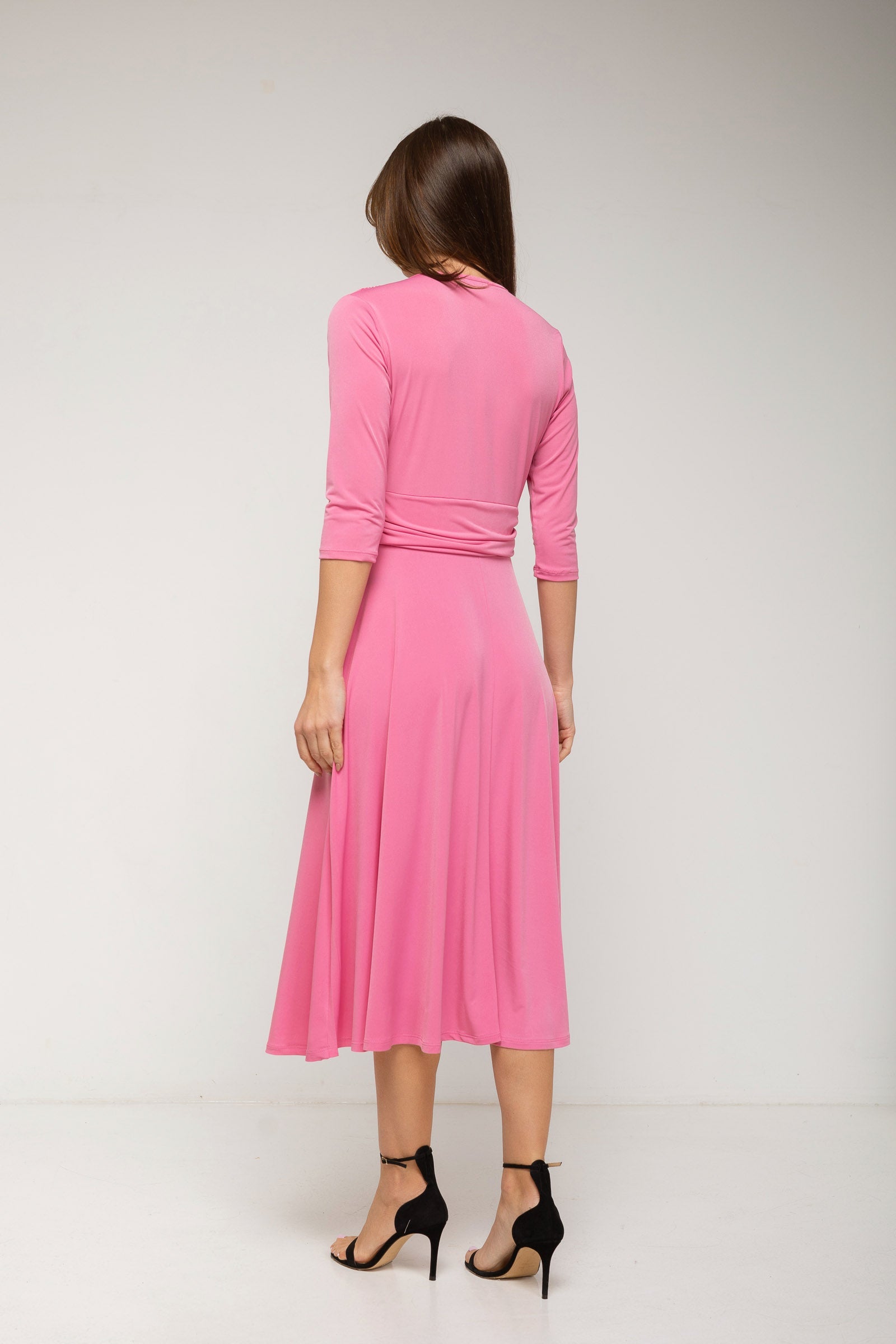 Woman wearing a pink dress with a plain background