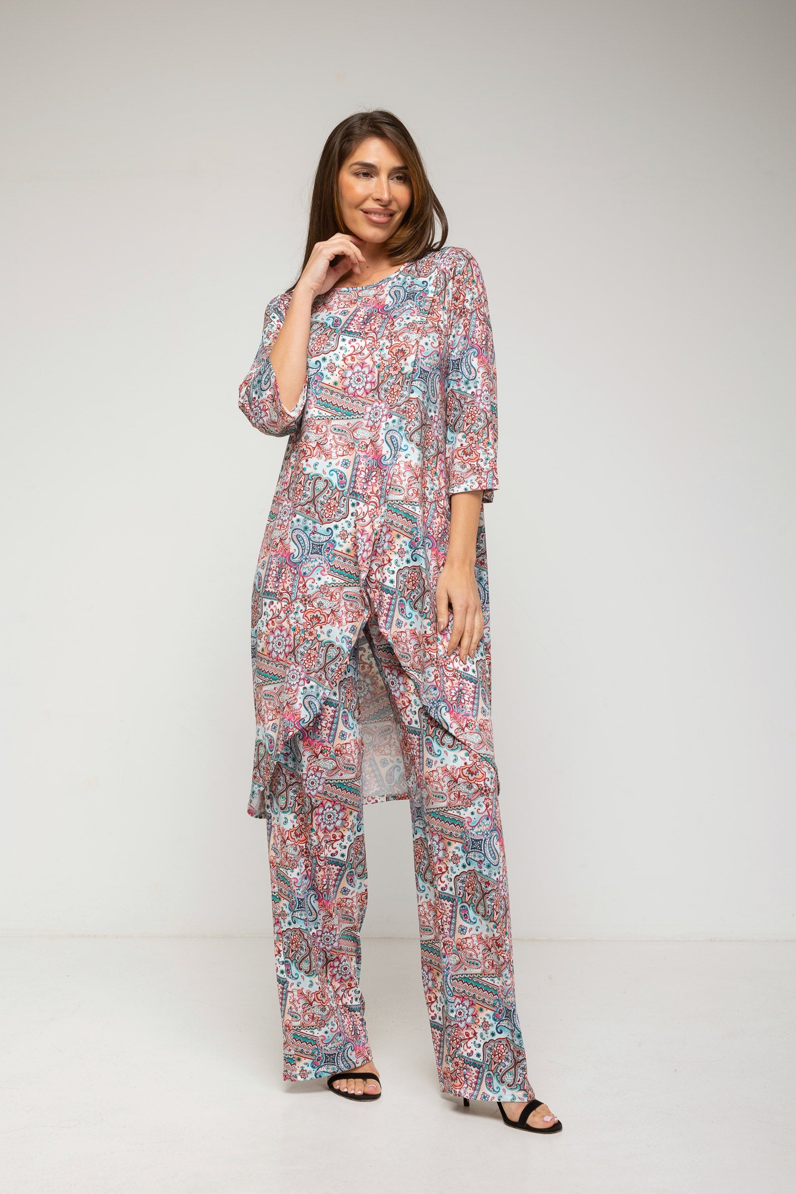 Woman wearing a patterned dress and pants set on a white background