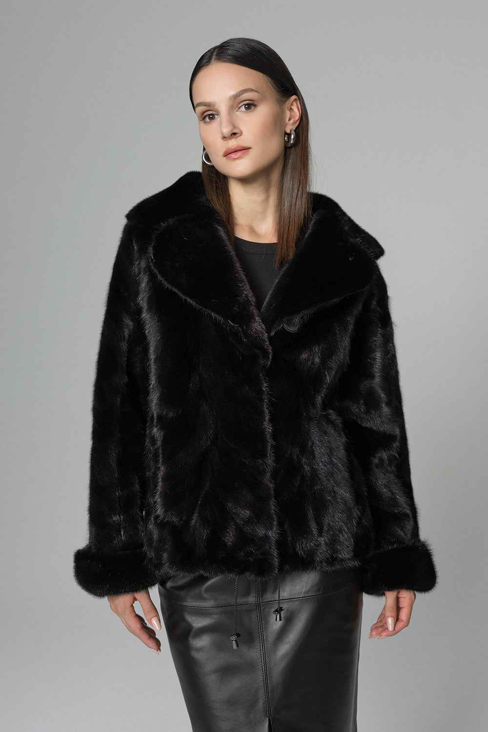 Woman wearing a black fur coat against a gray background