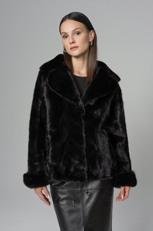 Woman wearing a black fur coat against a gray background