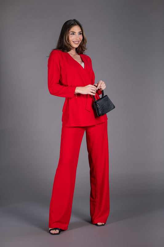 Woman in a red outfit holding a black handbag against a gray background
