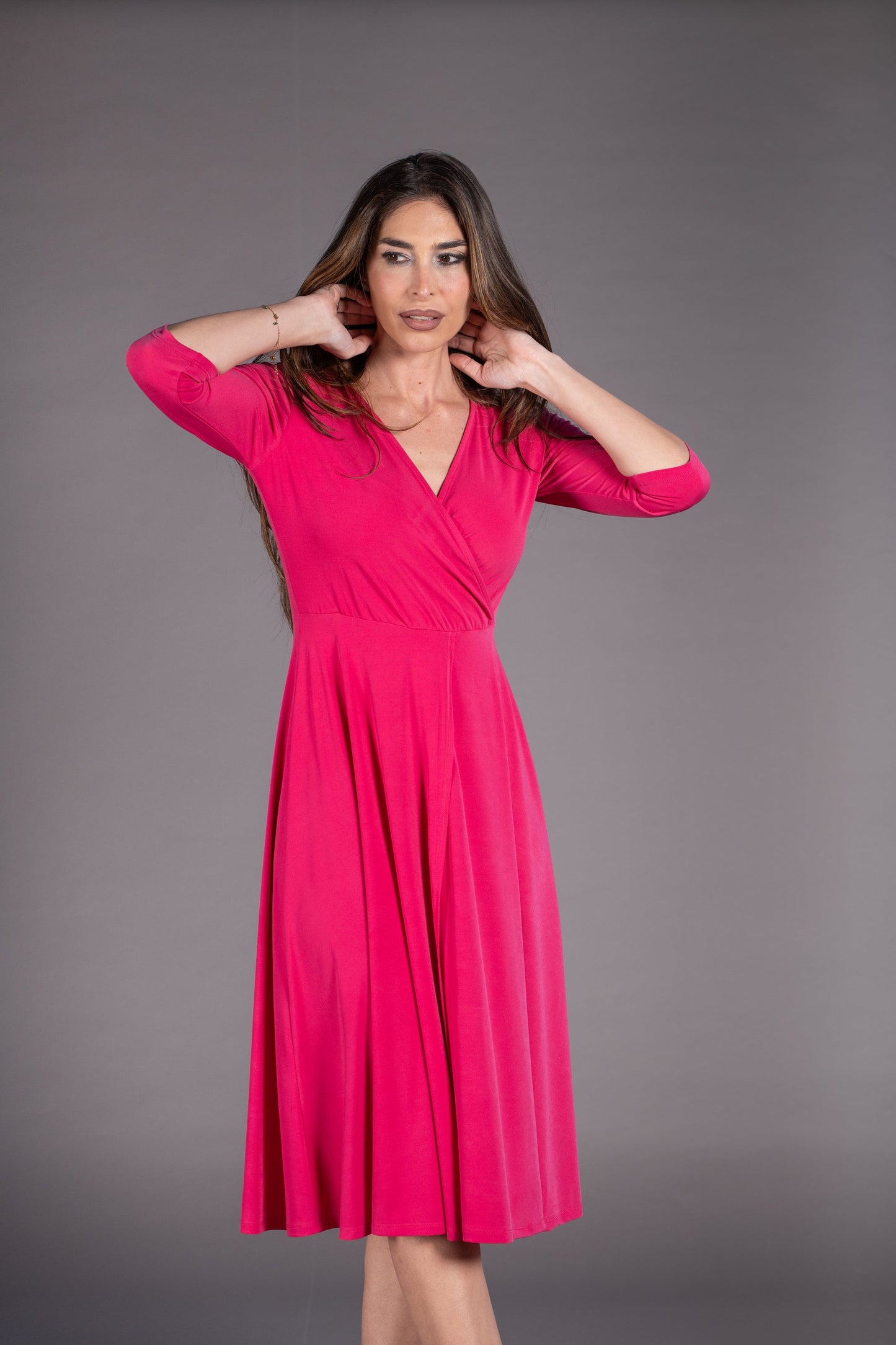 Woman wearing a bright pink dress against a gray background