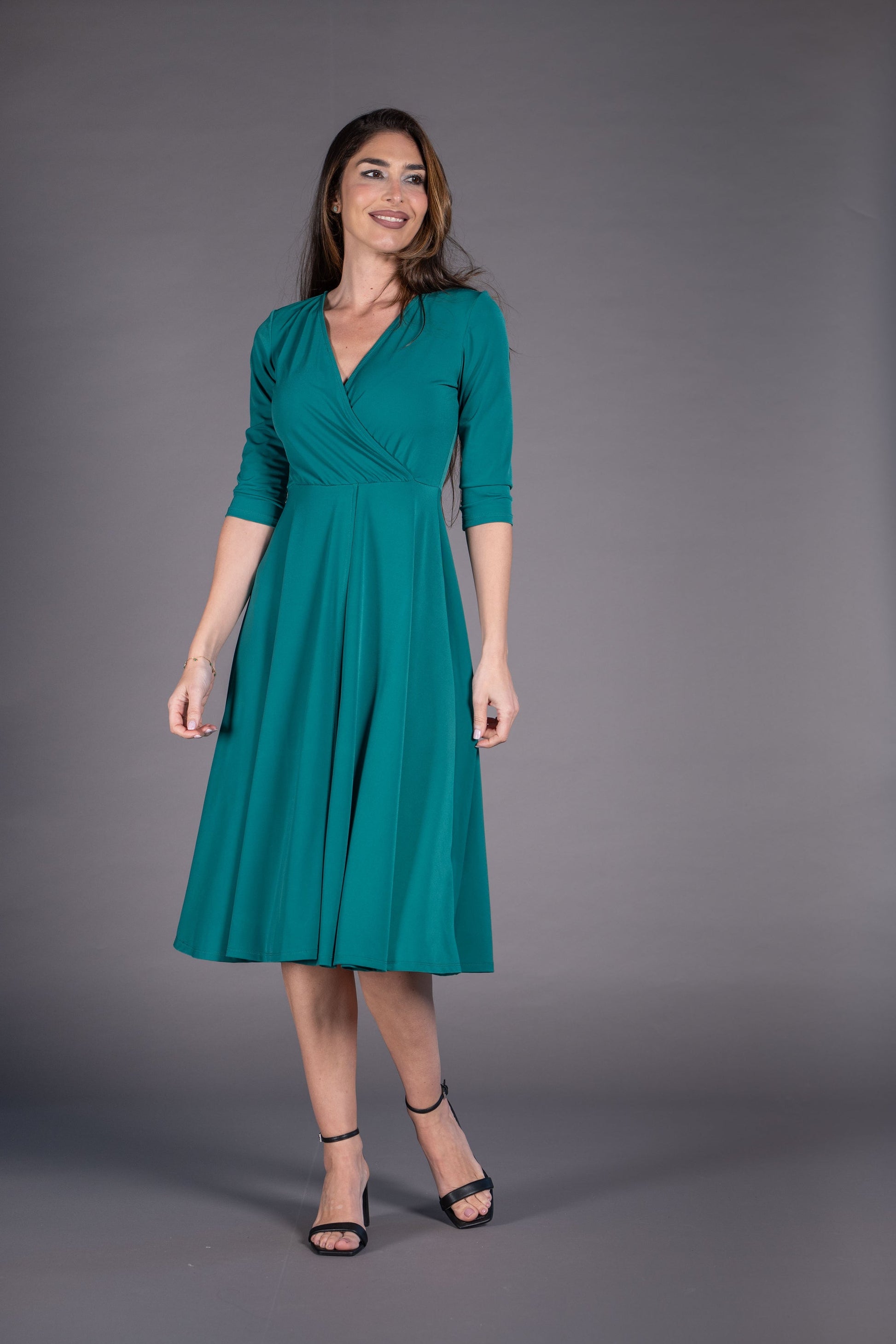 Woman wearing a teal dress against a gray background