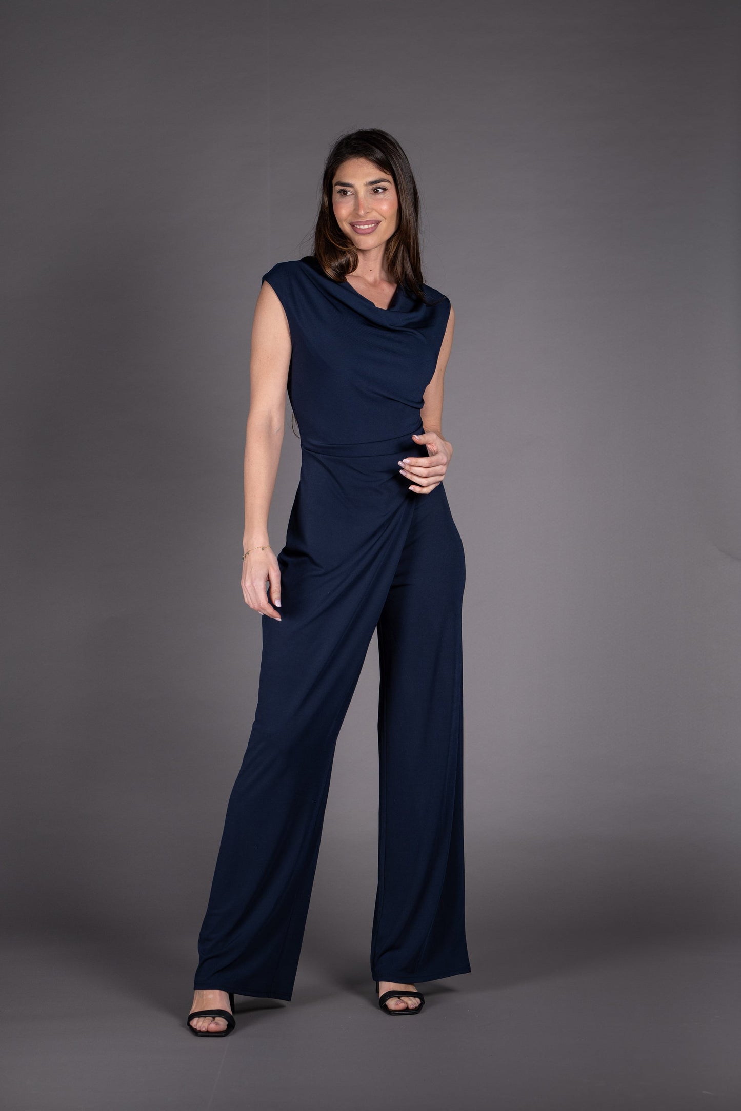 Woman wearing a navy blue jumpsuit against a gray background