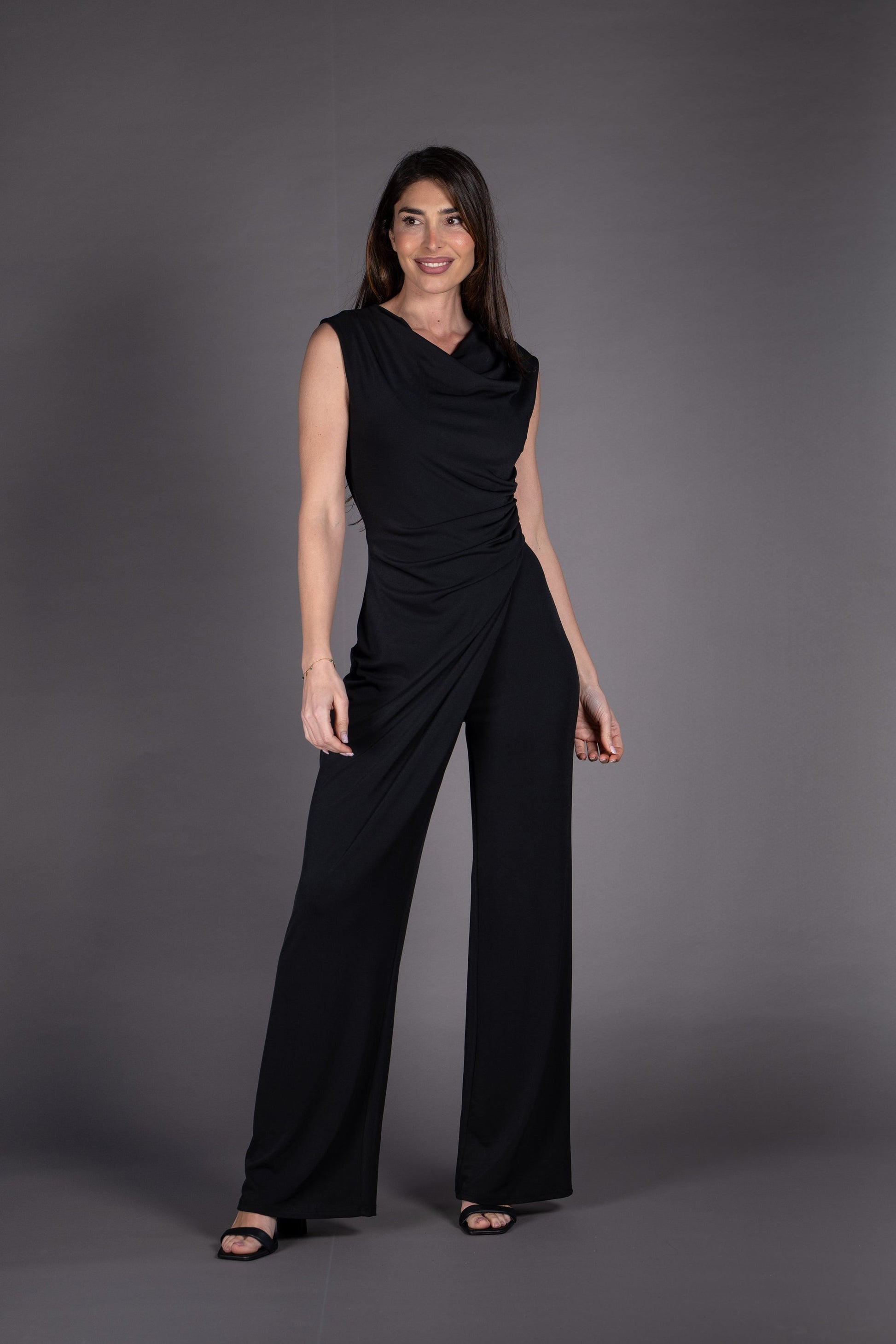 Woman wearing a black sleeveless top and pants against a gray background