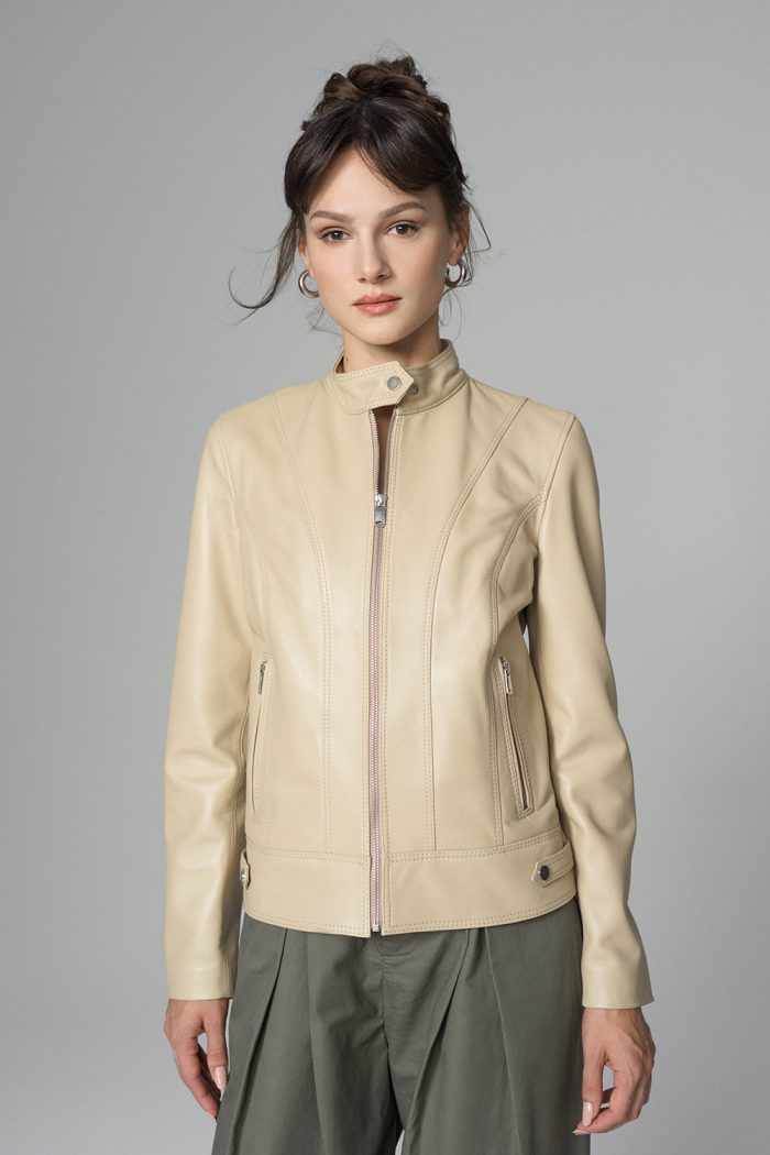 Woman wearing a beige leather jacket against a gray background