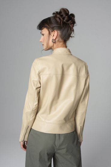 Woman wearing a beige leather jacket on a gray background