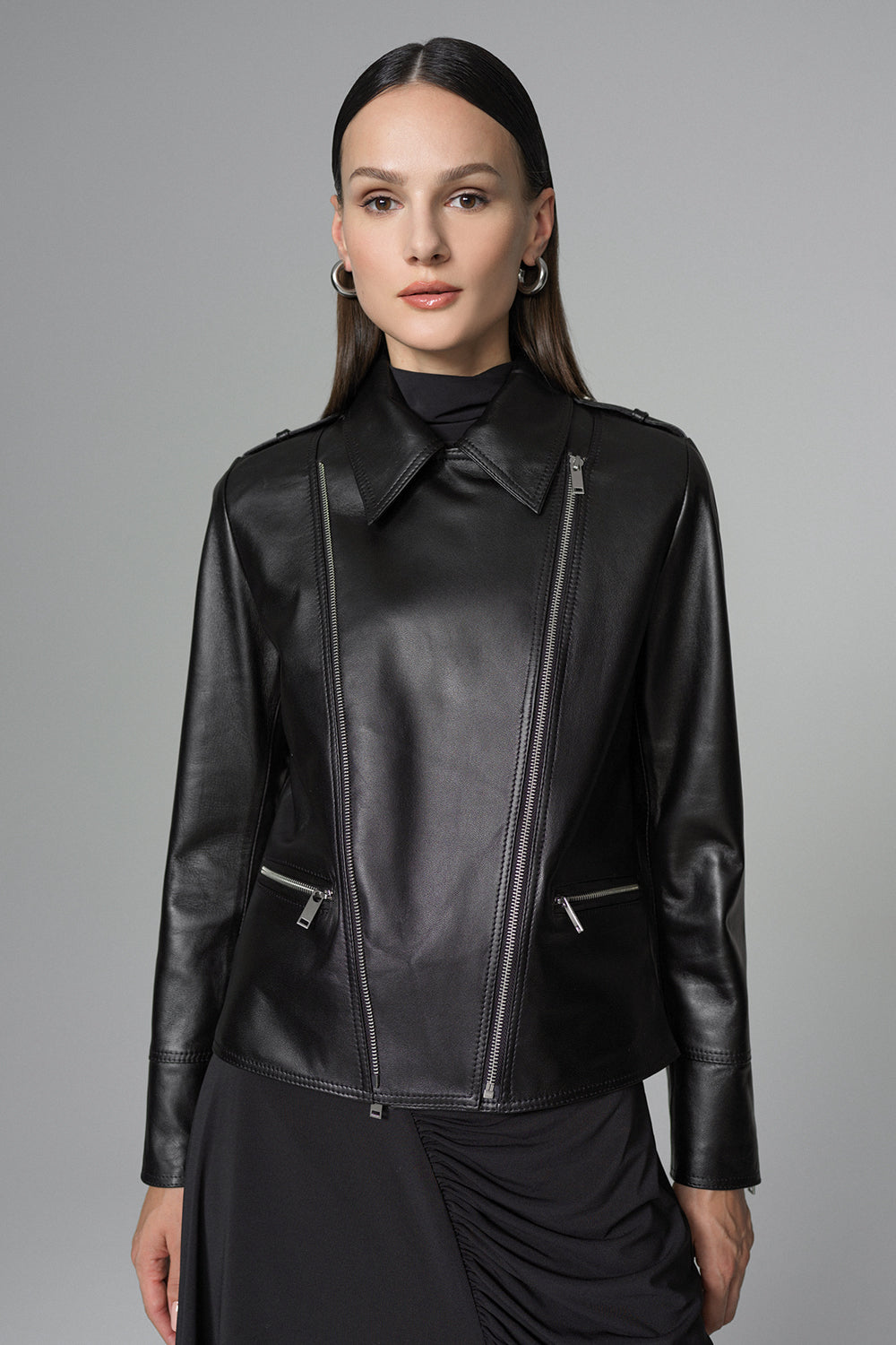 Woman wearing a black leather jacket against a gray background