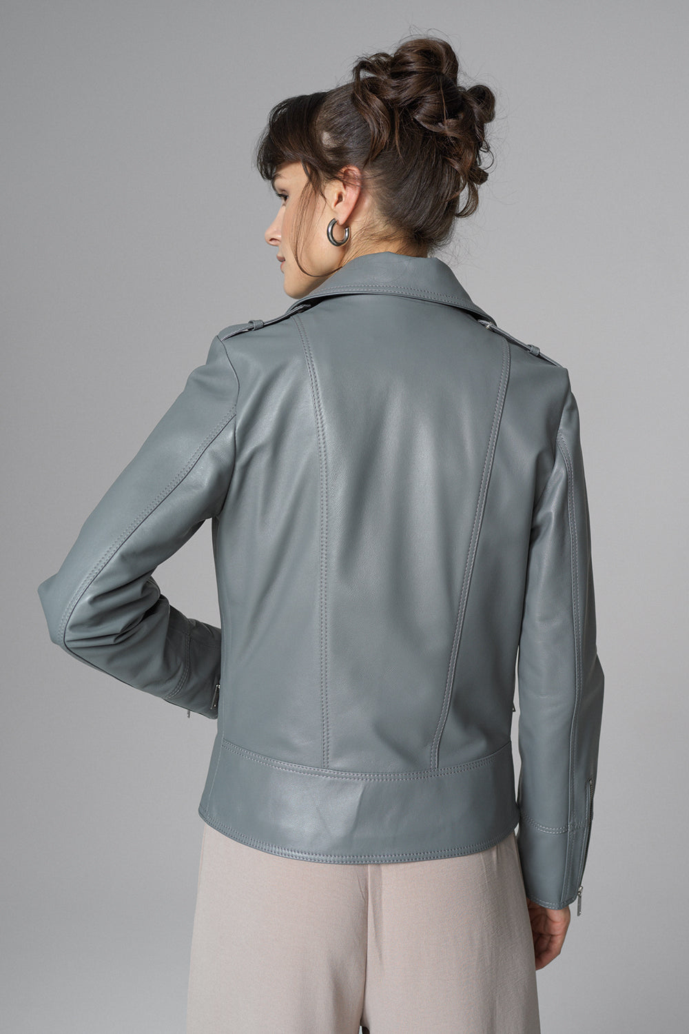 Woman wearing a gray leather jacket against a gray background
