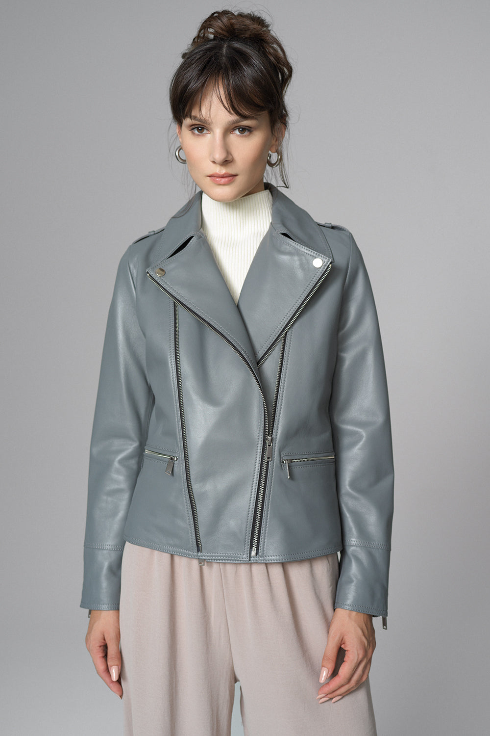 Woman wearing a gray leather jacket on a gray background
