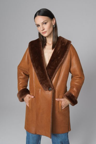 Woman wearing a brown leather coat with fur trim on a gray background
