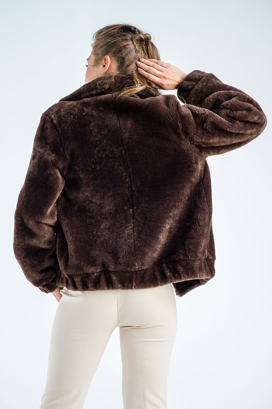 Person wearing a brown fur jacket on a light blue background