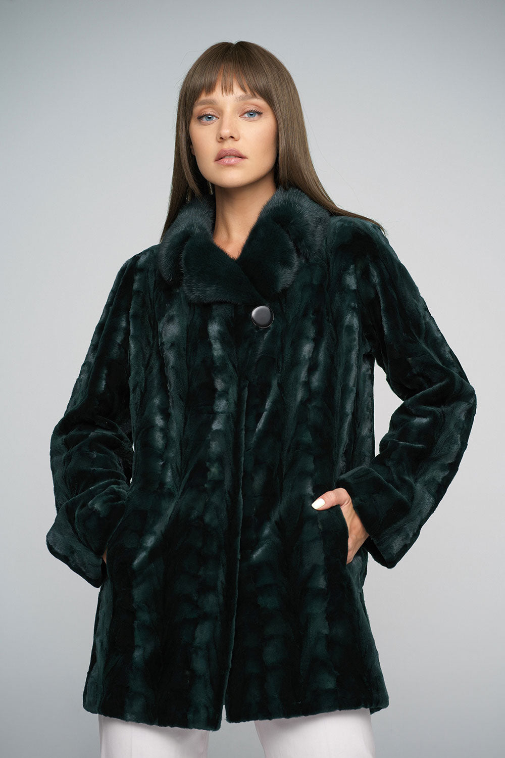 Woman wearing a dark green fur coat against a gray background