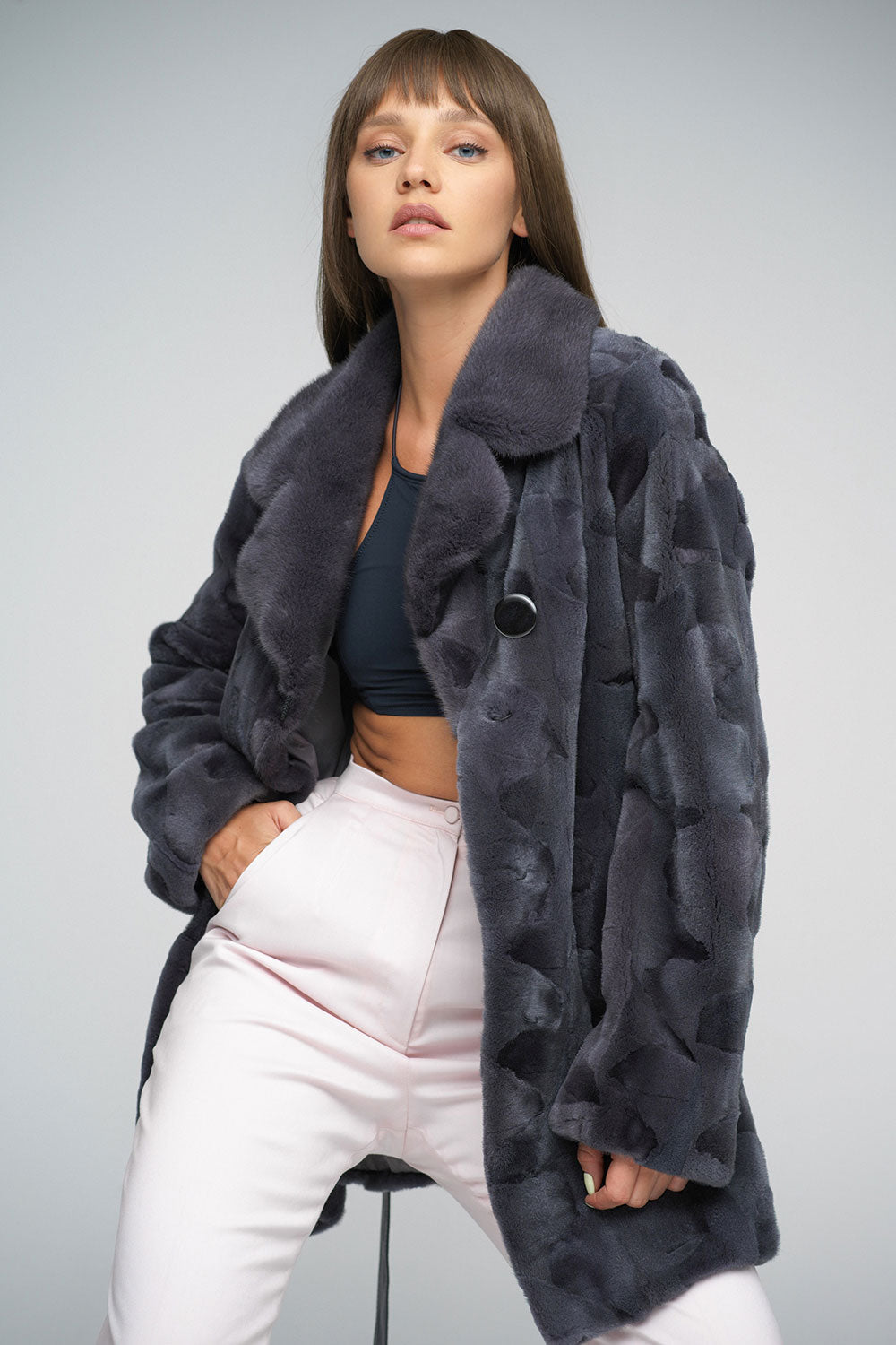 Woman wearing a dark gray fur coat on a plain background