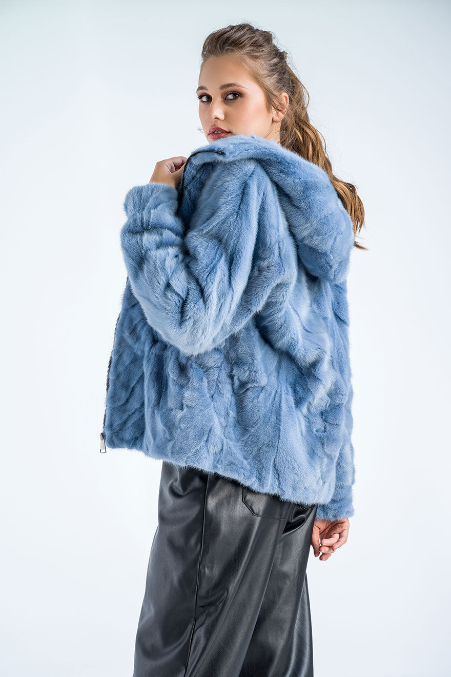 Woman wearing a blue fur coat against a white background