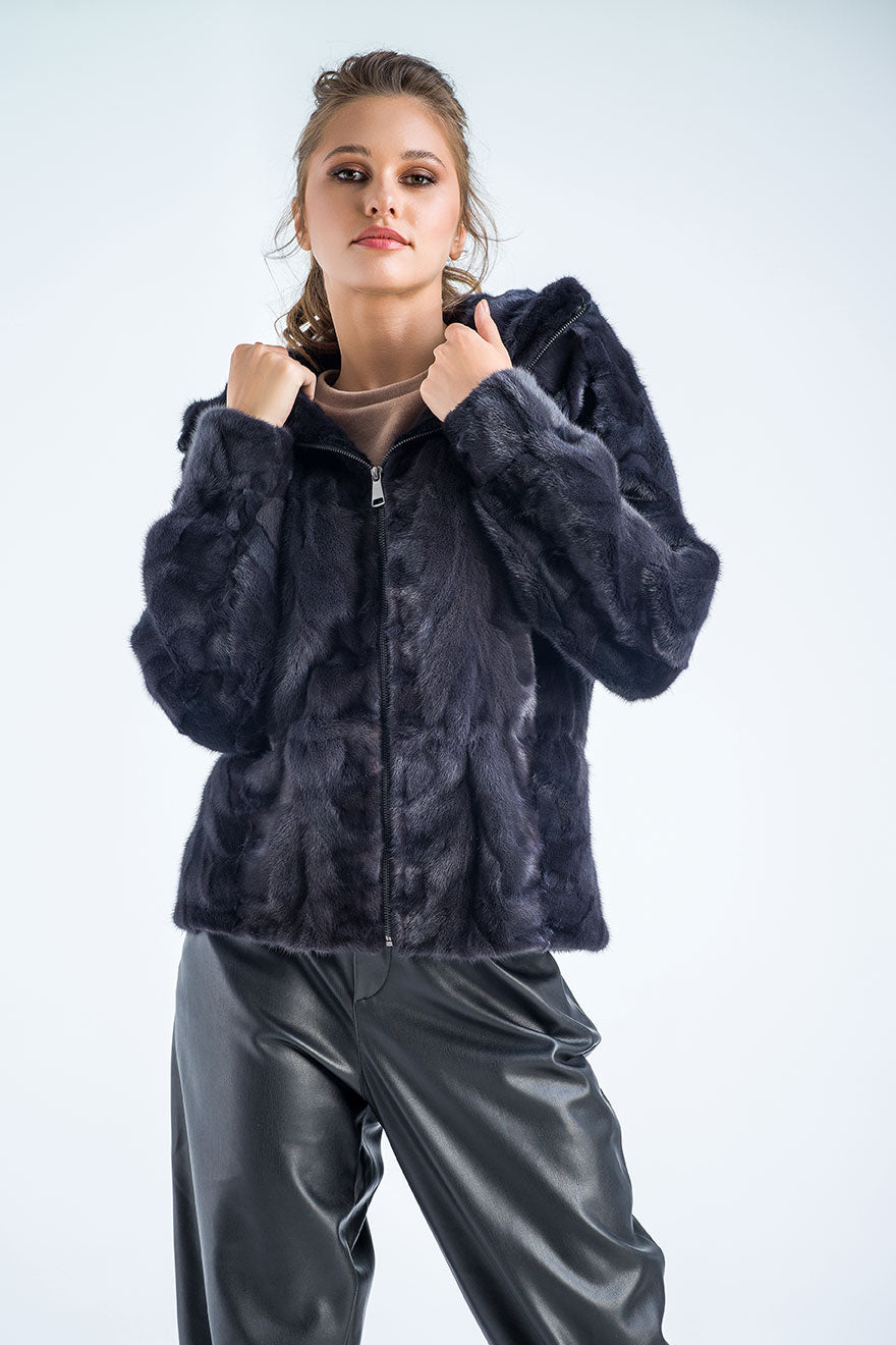 Person wearing a dark grey fur jacket and gray pants on a white background