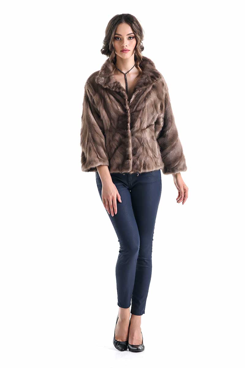 Woman wearing a brown fur coat and dark jeans on a white background