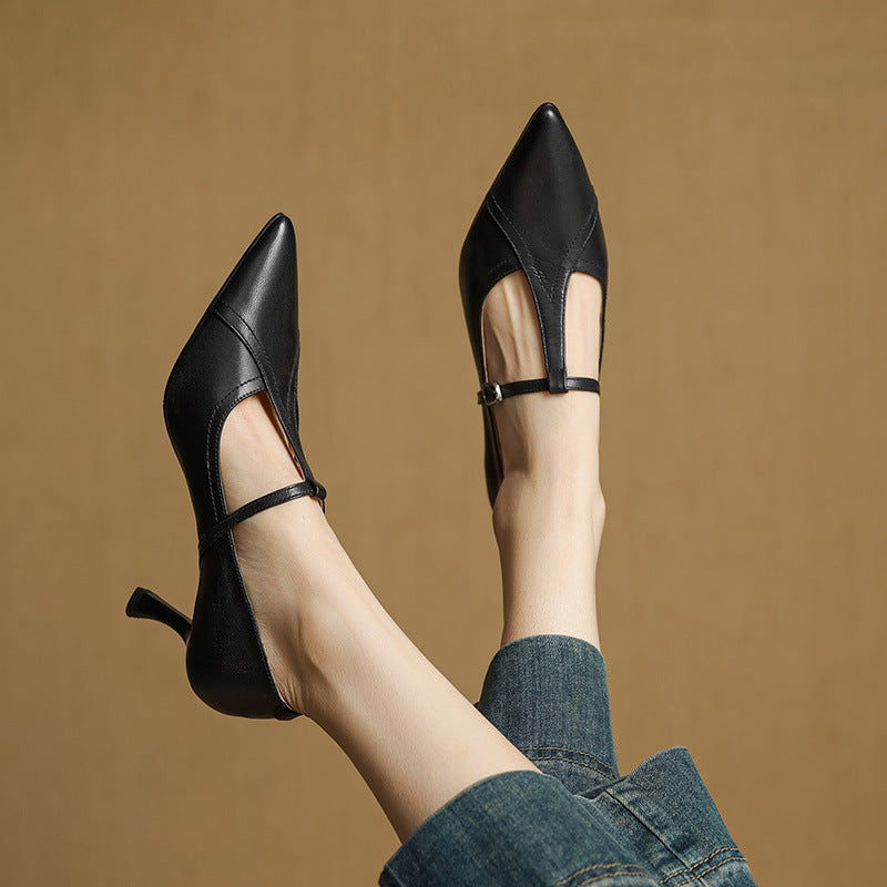 Black high-heeled shoes worn with blue jeans against a brown background