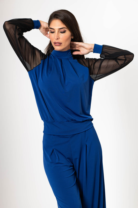 Woman wearing a blue outfit with sheer sleeves on a white background
