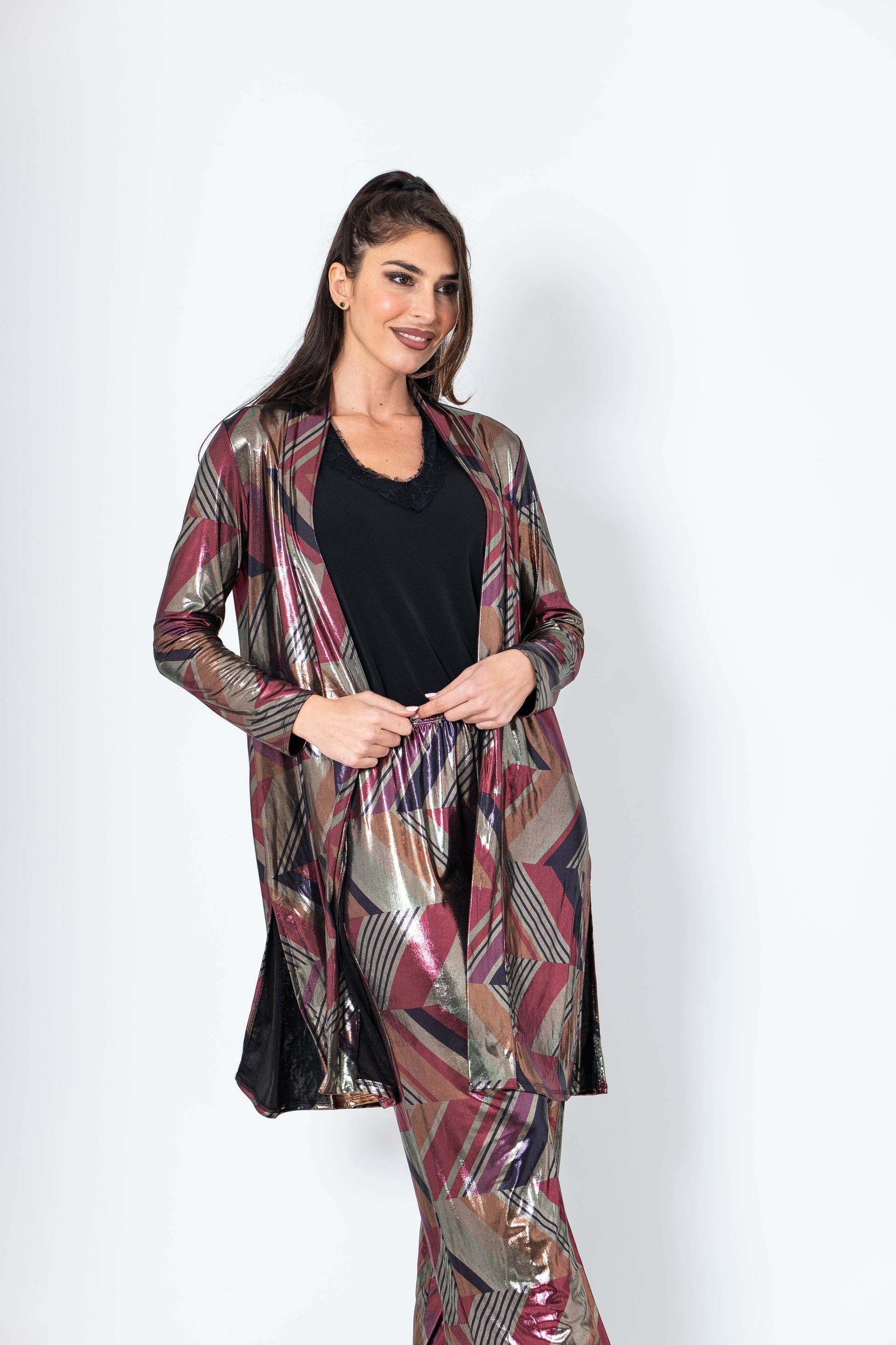 Woman wearing a patterned long coat over a black top on a white background