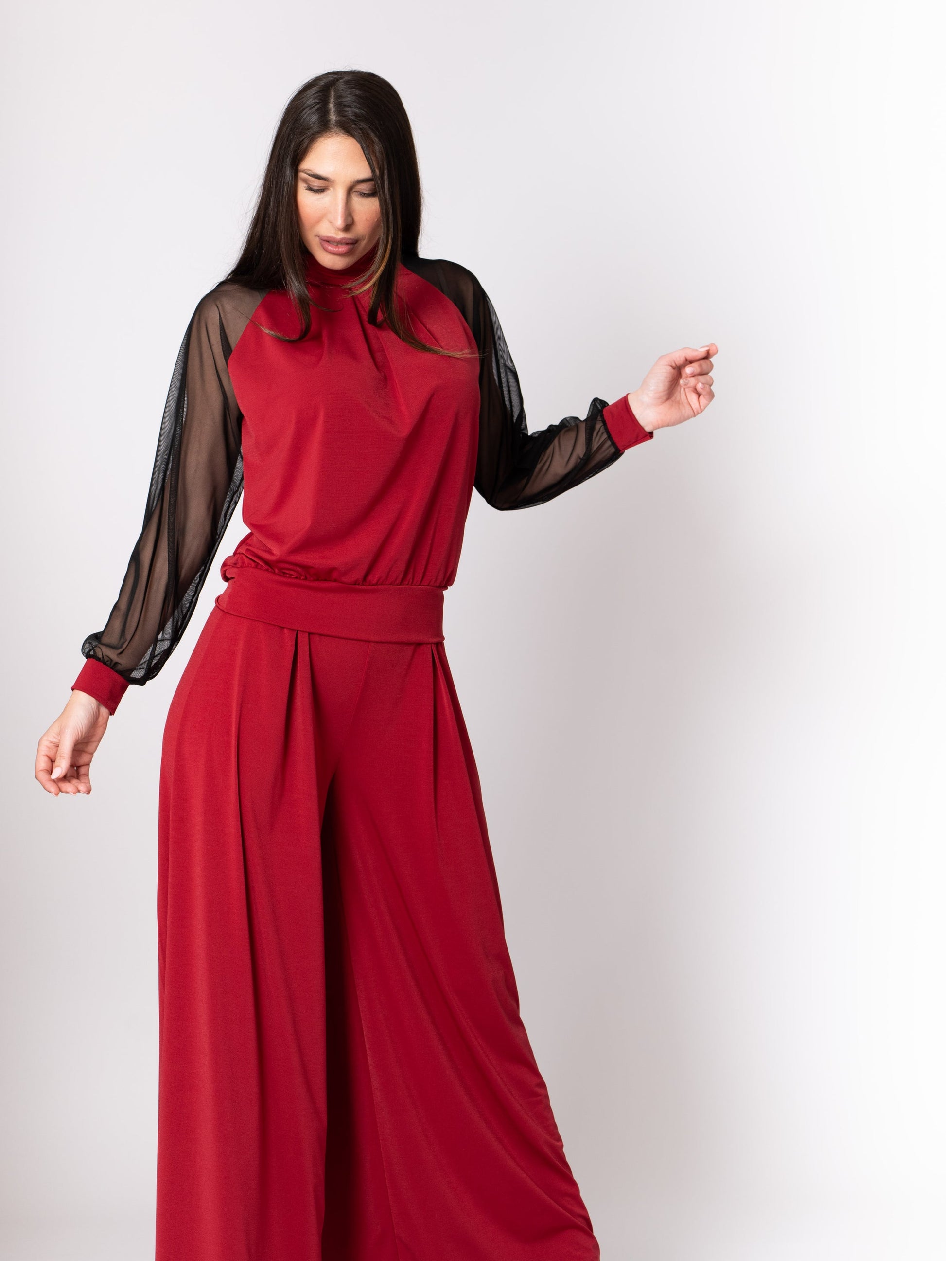 Woman wearing a red outfit with sheer black sleeves on a white background