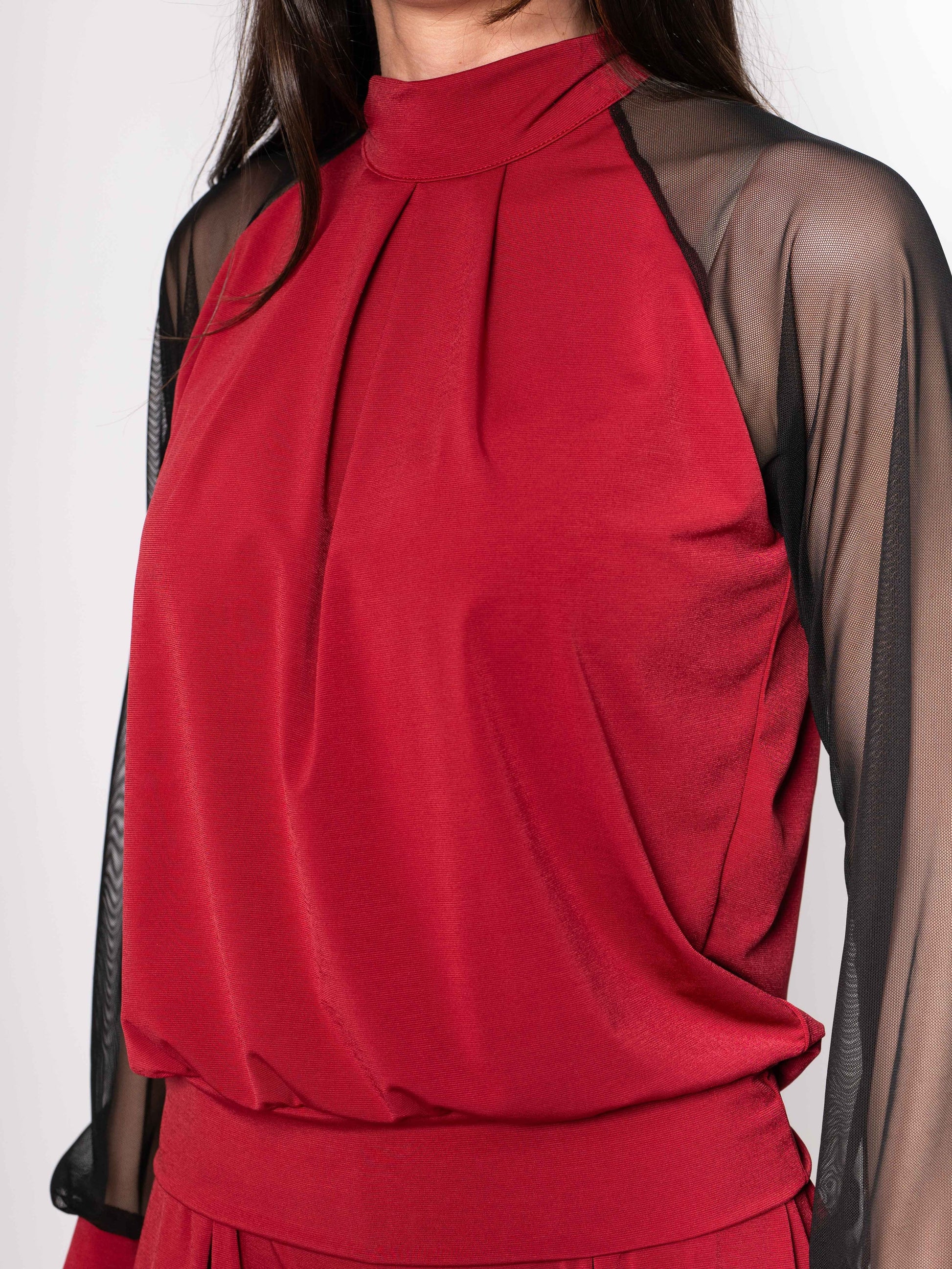 Red blouse with sheer black sleeves on a white background