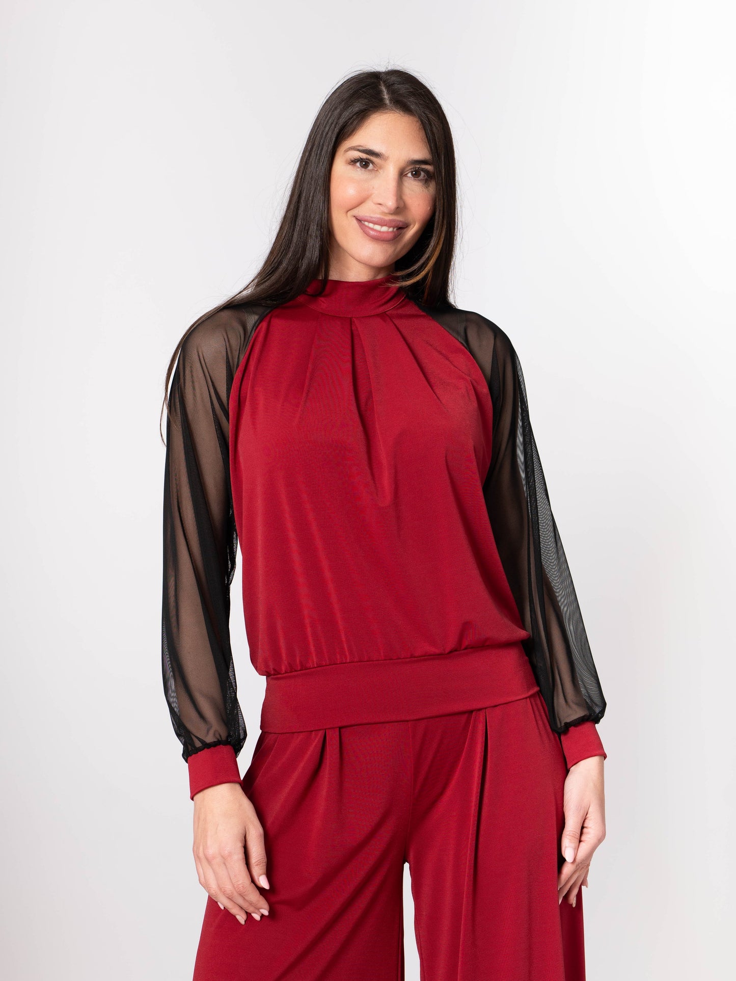 Woman wearing a red outfit with sheer sleeves on a white background