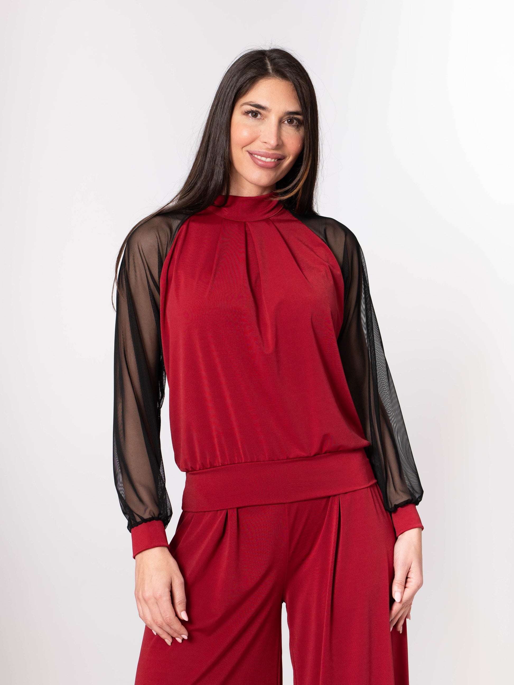 Woman wearing a red outfit with sheer sleeves on a white background