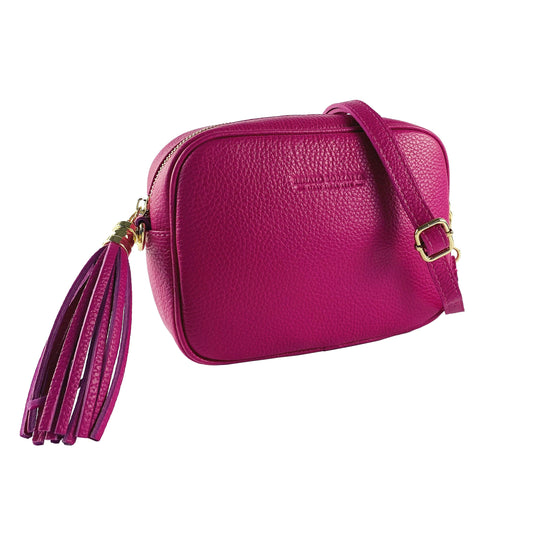 Pink leather crossbody bag with a tassel on a white background