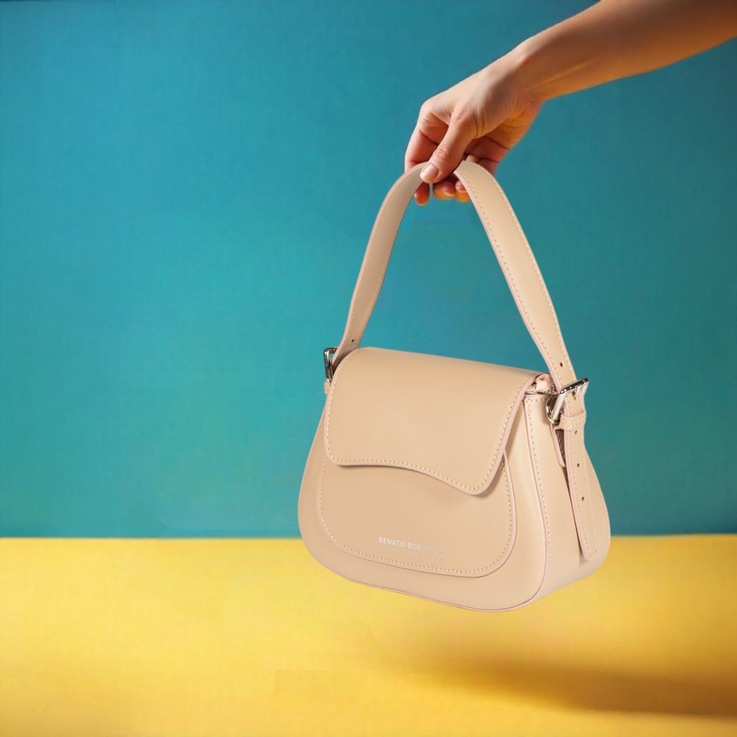 Beige handbag held by a hand against a blue and yellow background