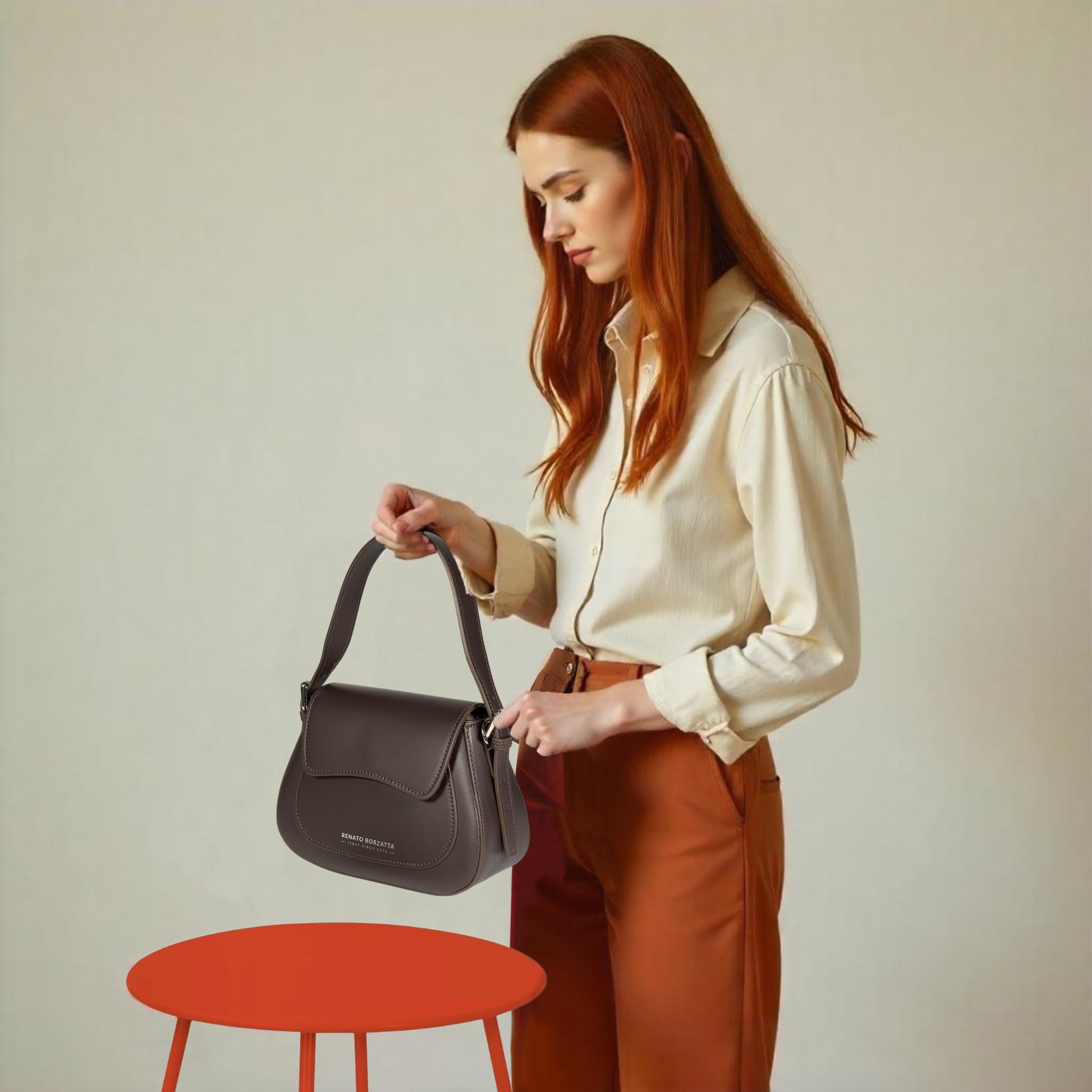 Woman holding a brown handbag with a plain background