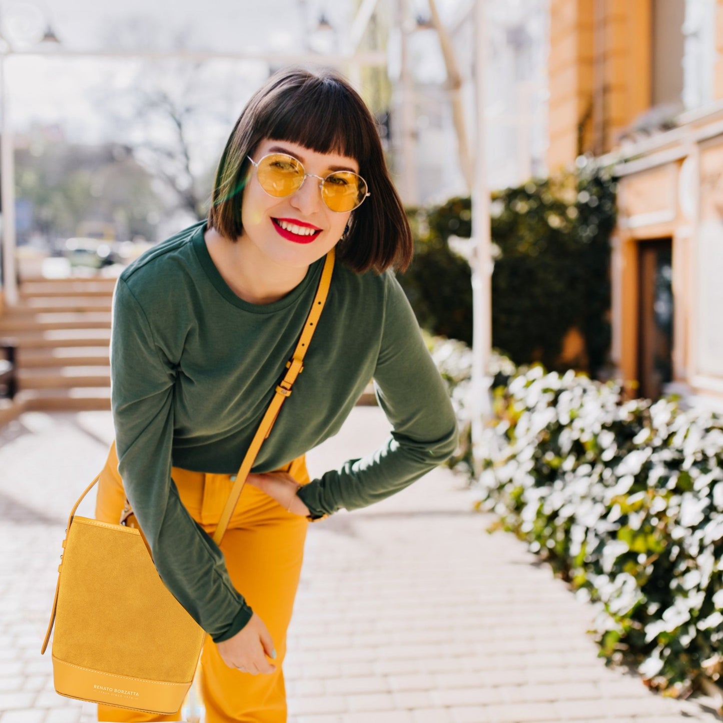 Woman wearing green top and yellow pants with sunglasses outdoors