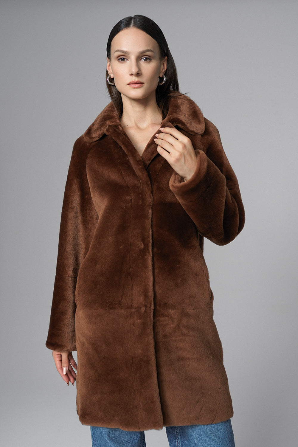 Woman wearing a brown fur coat against a gray background