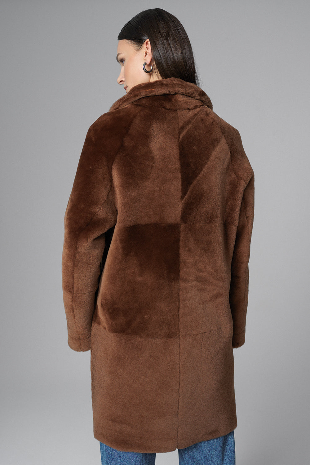 Woman wearing a brown fur coat against a gray background