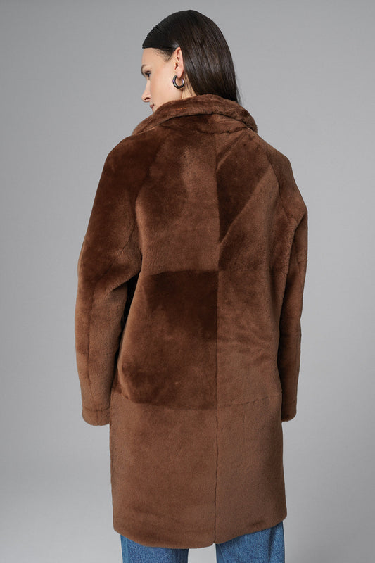 Woman wearing a brown fur coat against a gray background