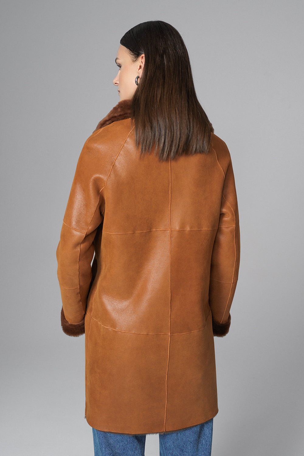 Person wearing a brown leather coat on a gray background