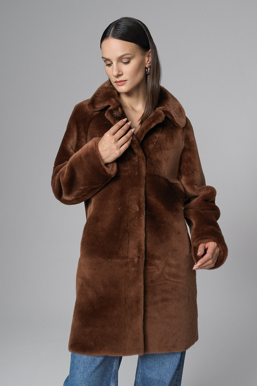 Woman wearing a brown fur coat against a gray background