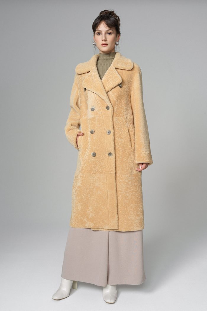 Woman wearing a beige coat on a plain background