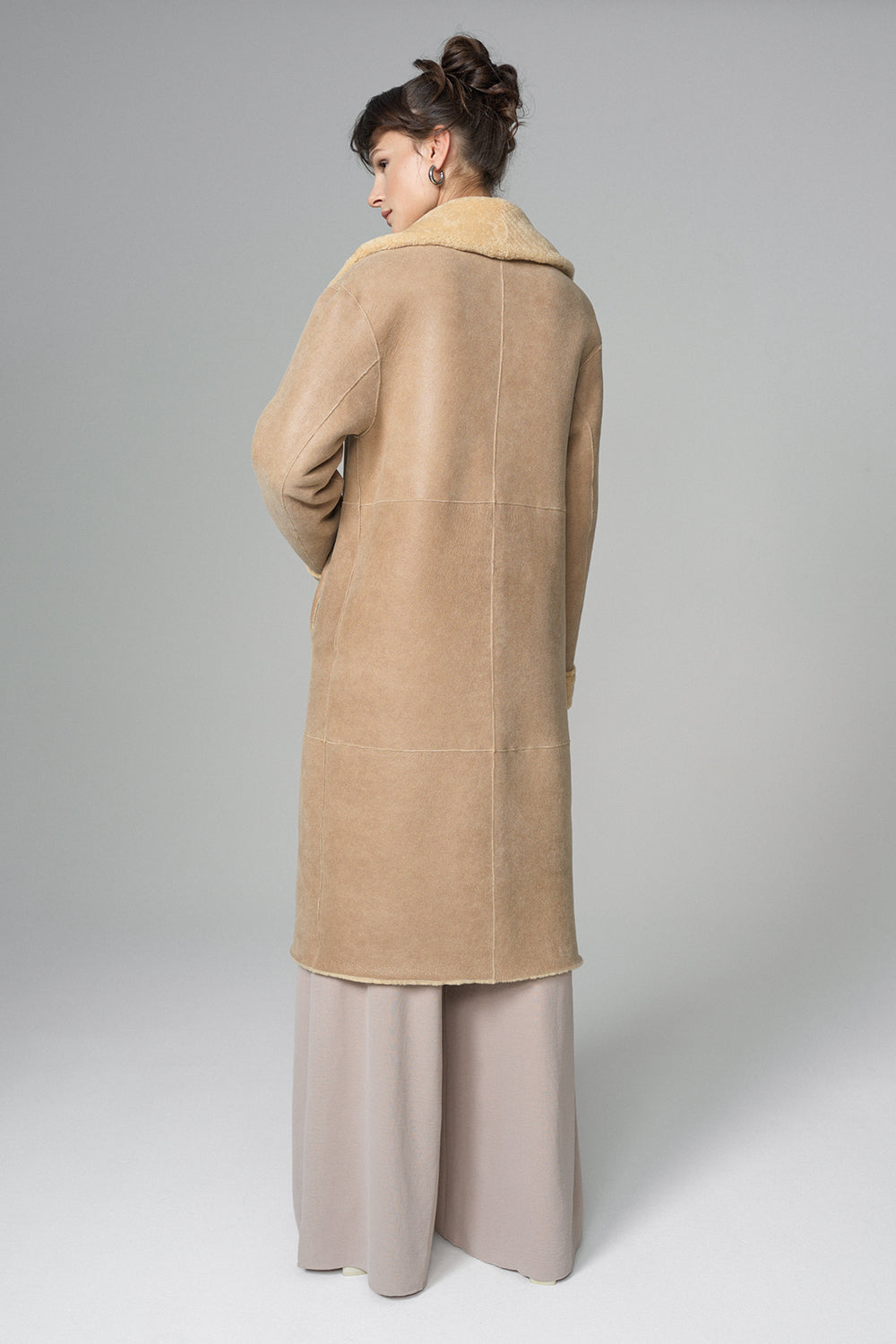 Woman wearing a beige coat on a plain background