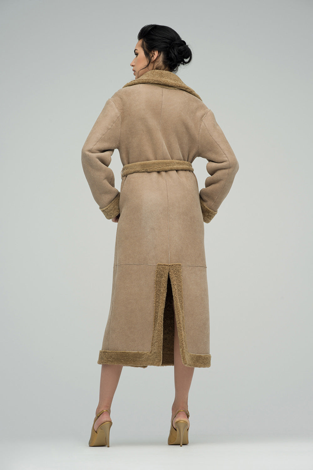 Woman wearing a beige coat with a belt on a white background