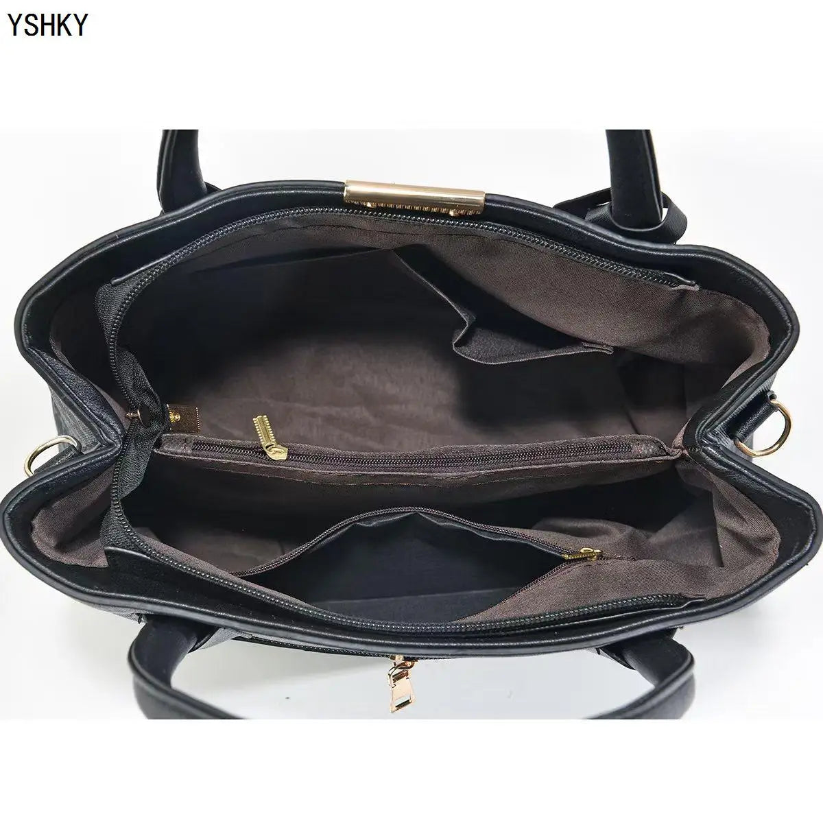 Black handbag with gold zippers on a white background