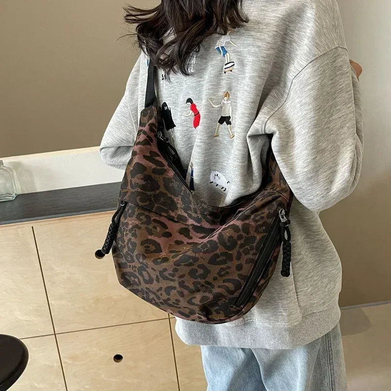 Person wearing a leopard print bag and gray sweatshirt with graphic design indoors.