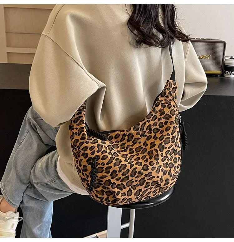 Person wearing a beige sweater and holding a leopard print bag indoors.
