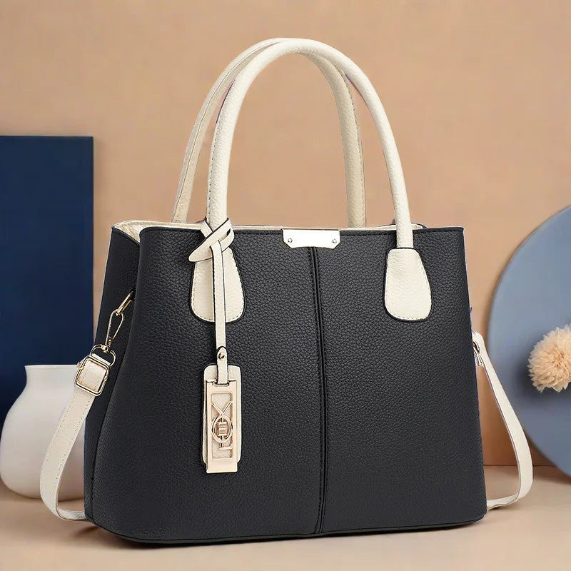 Black handbag with white handles and accents on a beige background