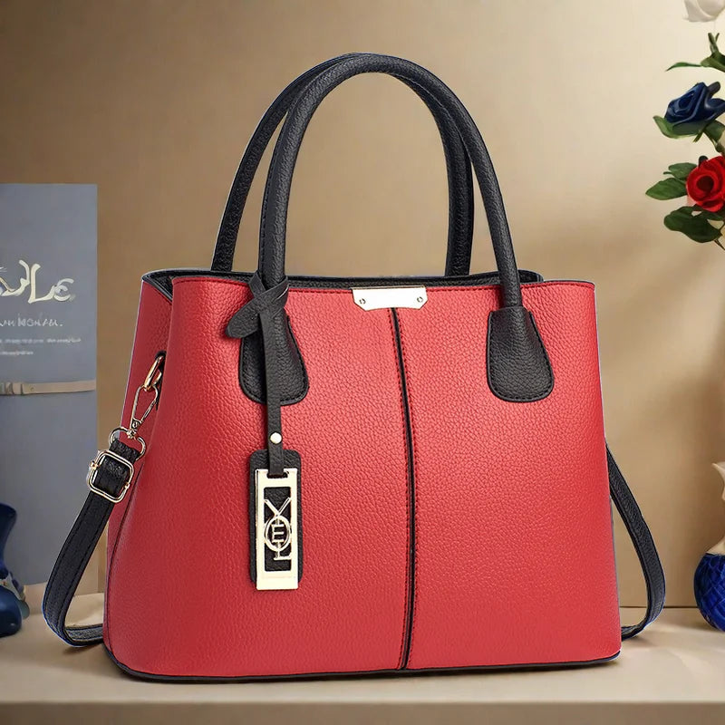 Red handbag with black handles and trim on a beige surface